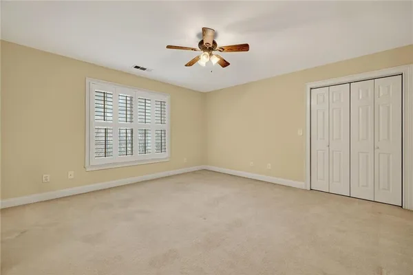 an empty room with ceiling fan and window