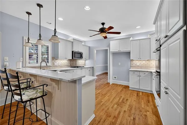 a kitchen with stainless steel appliances granite countertop a sink a stove a refrigerator and island with wooden floor