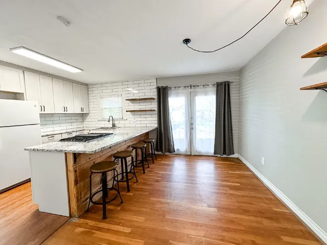 a kitchen with stainless steel appliances granite countertop a stove top oven a sink dishwasher and a refrigerator with wooden floor