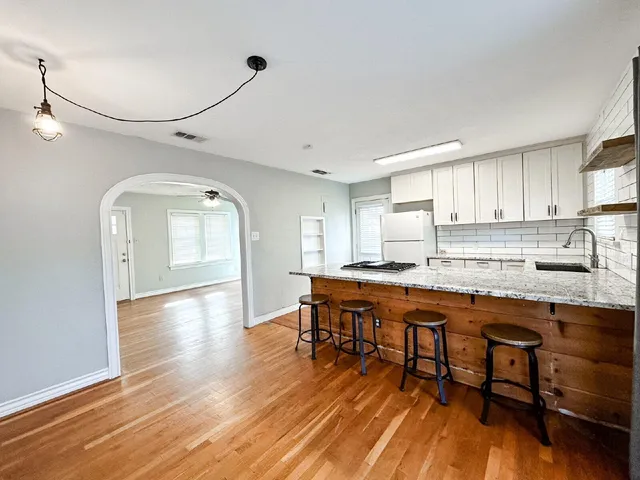 a kitchen with stainless steel appliances granite countertop a table chairs sink refrigerator and cabinets
