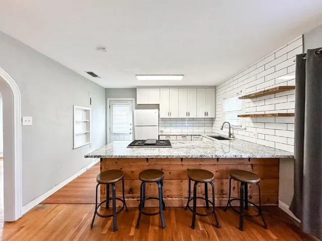a kitchen with granite countertop white cabinets and wooden floor