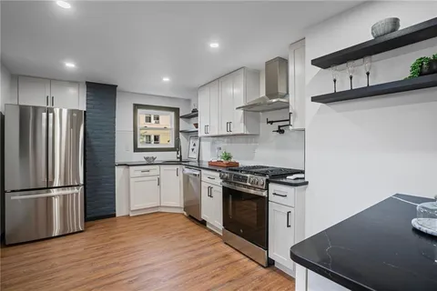a kitchen with stainless steel appliances granite countertop a refrigerator a stove and a sink