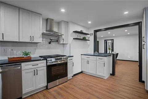a kitchen with stainless steel appliances granite countertop a stove and white cabinets