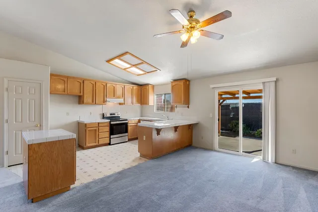 a kitchen with stainless steel appliances granite countertop a sink a stove top oven a chimney cabinets and a dining table