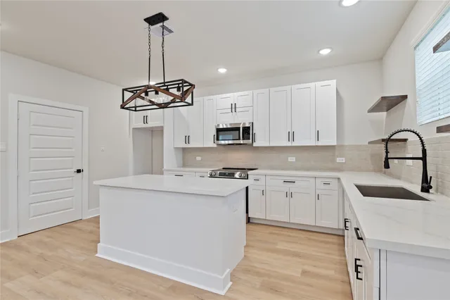 a kitchen with kitchen island a sink stainless steel appliances and cabinets