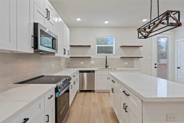 a kitchen with stainless steel appliances granite countertop a sink stove and microwave