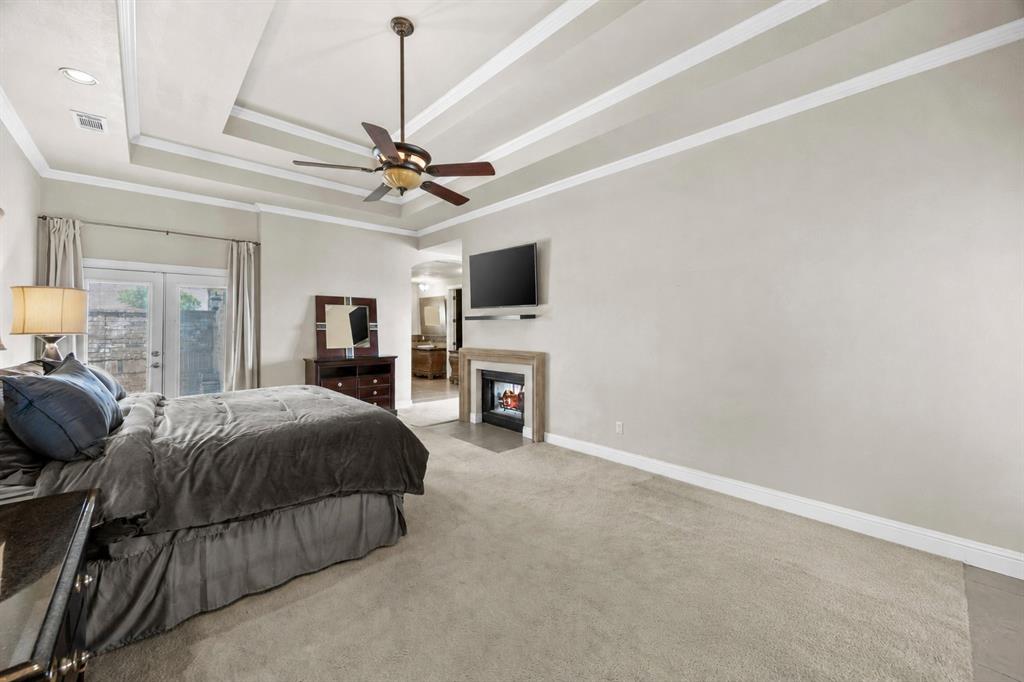 219 Mohundro Road Ferris, TX 75125 - Photo 18 of 40 a spacious bedroom with a bed a fireplace and a flat screen tv