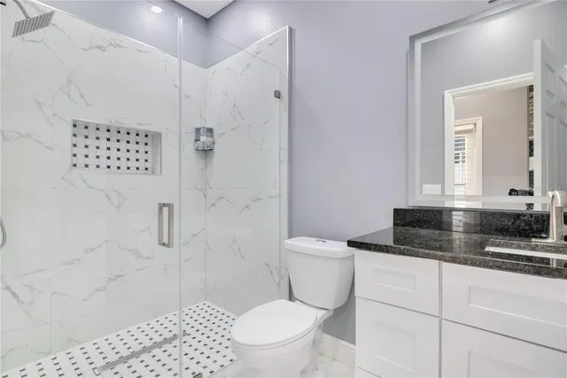 a bathroom with a granite countertop sink a mirror and a toilet