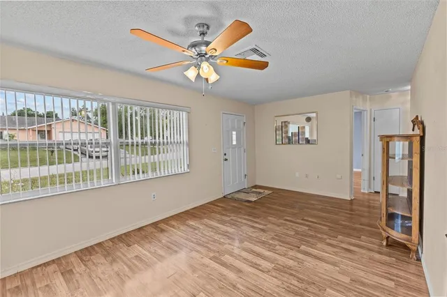 a view of empty room with wooden floor and fan