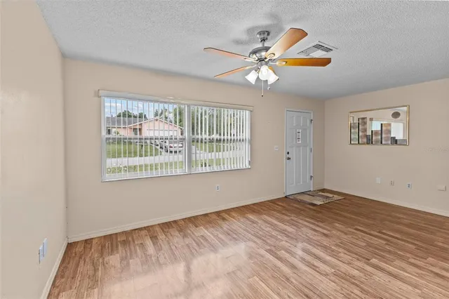 a view of an empty room with window and wooden floor