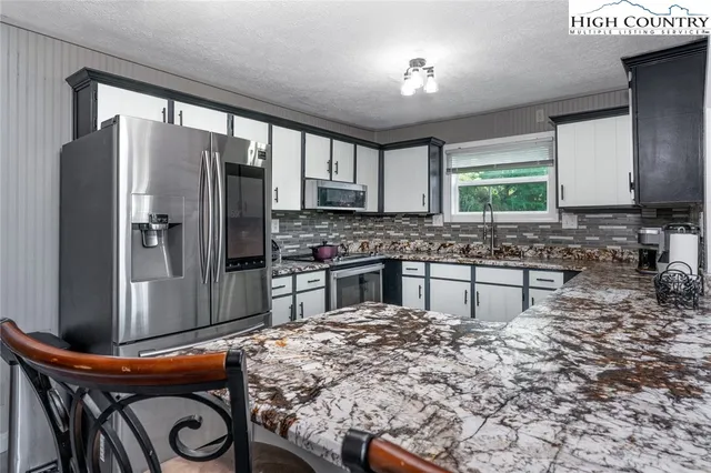a kitchen with stainless steel appliances granite countertop a stove a refrigerator and a microwave