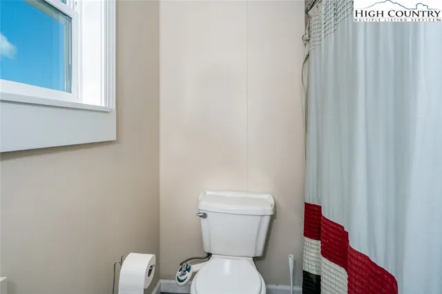 a white toilet sitting next to a small window