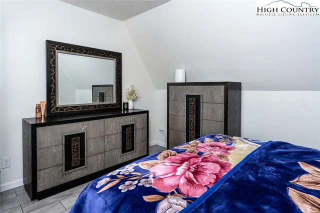 a bedroom with a bed and a dresser with mirror