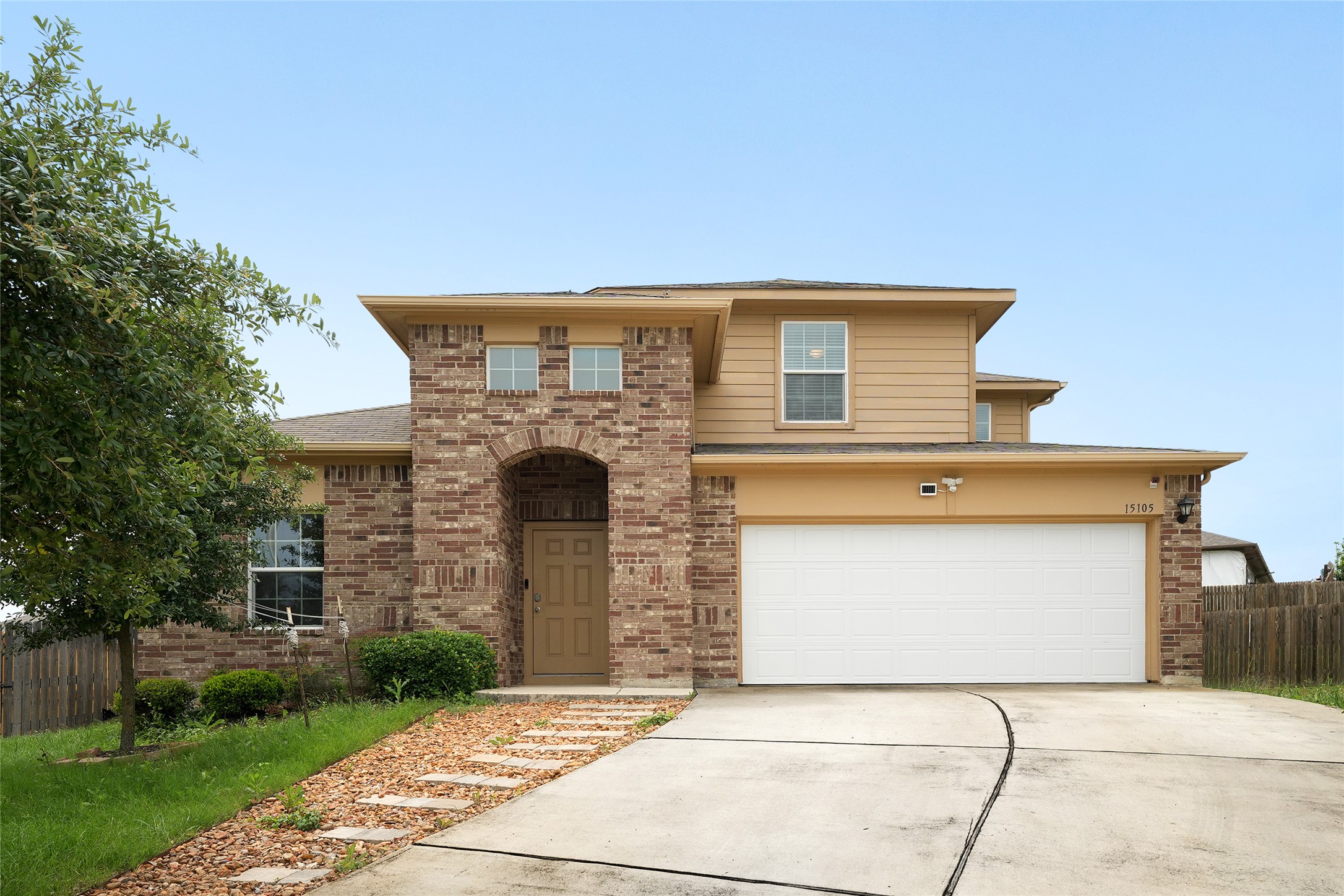 15105 Shell Bark Cove Austin, TX 78724 - Photo 1 of 30 A well-maintained facade features a prominent arched entryway and an attached garage with a wide concrete driveway.