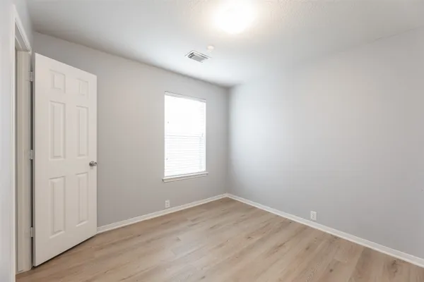 an empty room with wooden floor and window