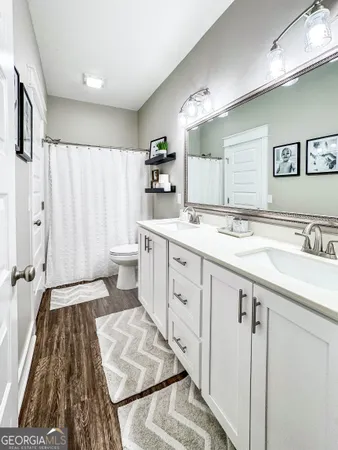a spacious bathroom with a double vanity sink a mirror and a shower