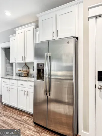 a kitchen with granite countertop stainless steel appliances a refrigerator a stove top oven and white cabinets