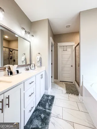 a spacious bathroom with a double vanity sink a mirror and a shower