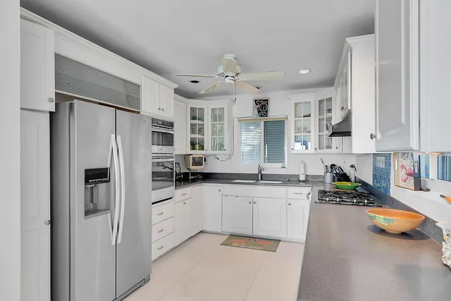 a kitchen with stainless steel appliances a refrigerator sink and white cabinets