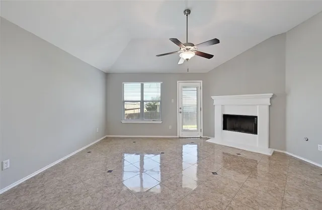 an empty room with windows and fireplace