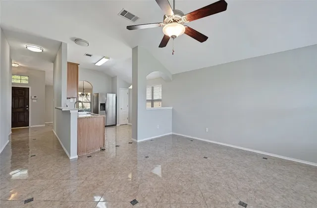 an empty room with kitchen and ceiling fan