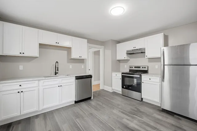 a kitchen with stainless steel appliances white cabinets and a refrigerator