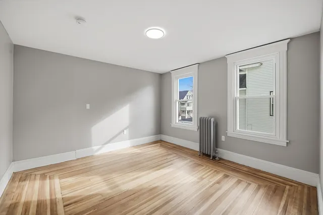 a view of empty room with window and wooden floor