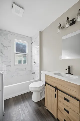 a bathroom with a granite countertop sink toilet a mirror and bathtub
