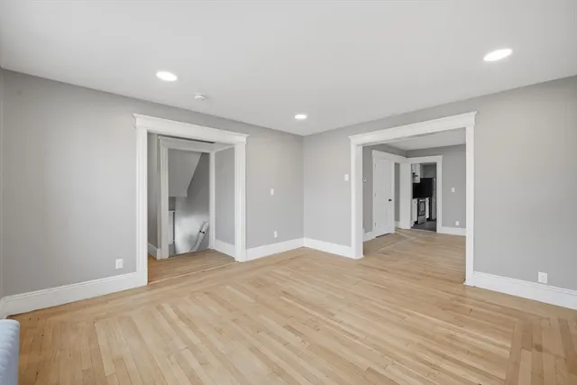 an empty room with wooden floor and natural light