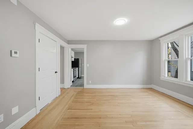 a view of an empty room with wooden floor and a window