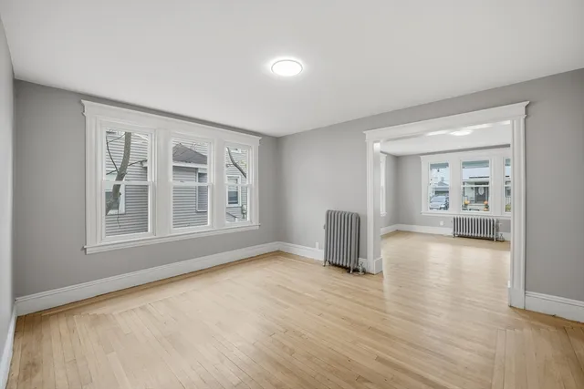a view of an empty room with a window and wooden floor