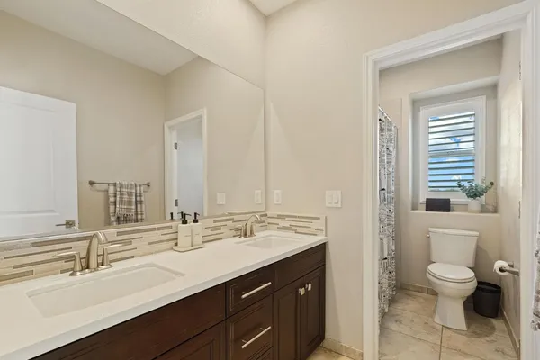 a bathroom with a double vanity sink toilet and a mirror