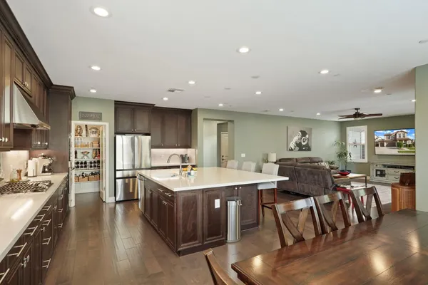 a kitchen with stainless steel appliances a dining table chairs and wooden floor