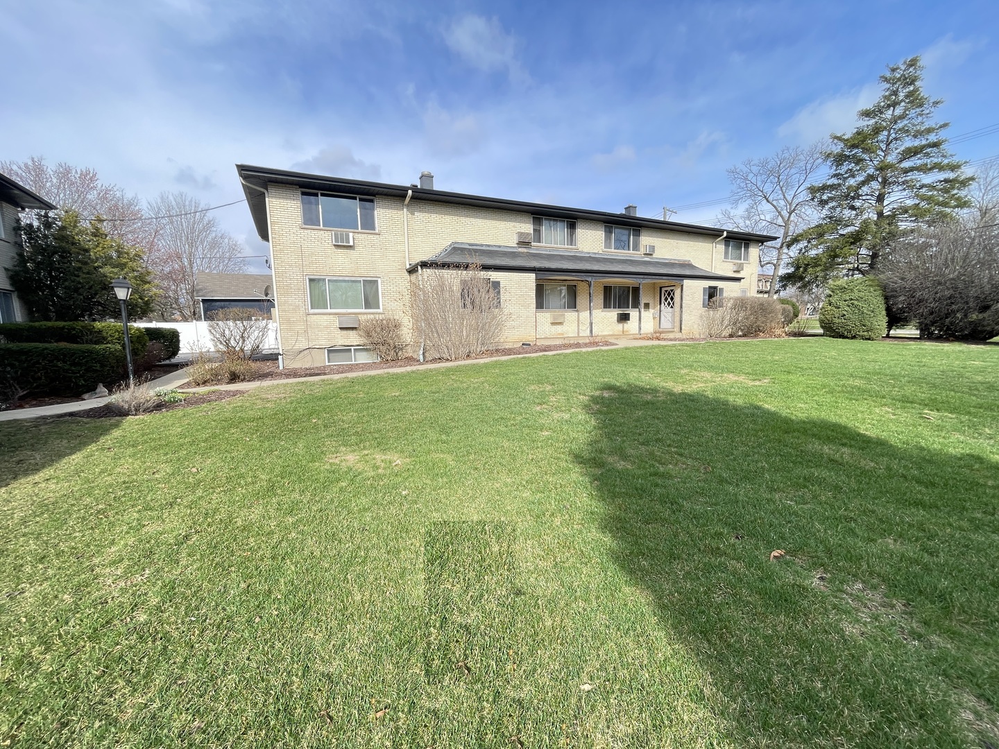 235 East Palatine Road, Unit 2B Palatine, IL 60067 - Photo 10 of 12 a view of a house with a big yard potted plants and large tree