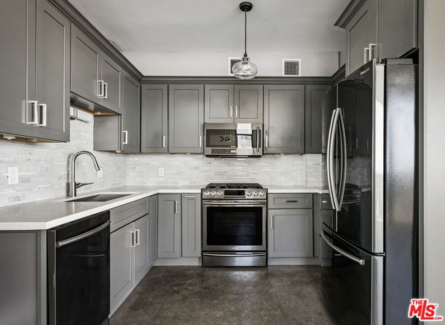 a kitchen with white cabinets a sink stove and a granite counter top