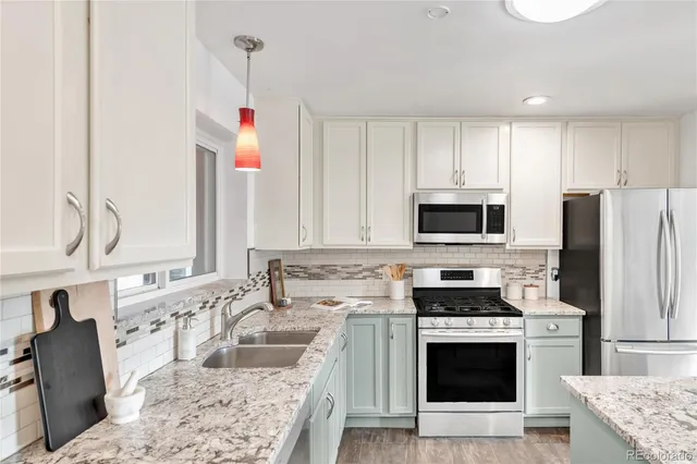 a kitchen with stainless steel appliances granite countertop a stove a sink and a refrigerator