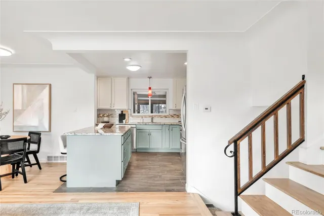 a living room with stainless steel appliances lots of wooden furniture a refrigerator a stove top oven and cabinets