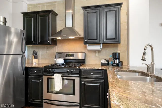 a kitchen with stainless steel appliances granite countertop a stove a refrigerator and a sink