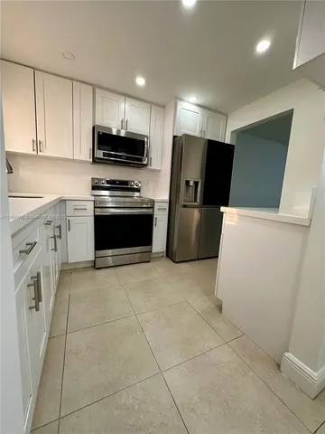 a kitchen with a refrigerator a stove top oven and cabinets