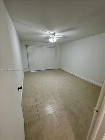 an empty room with a ceiling fan and carpet
