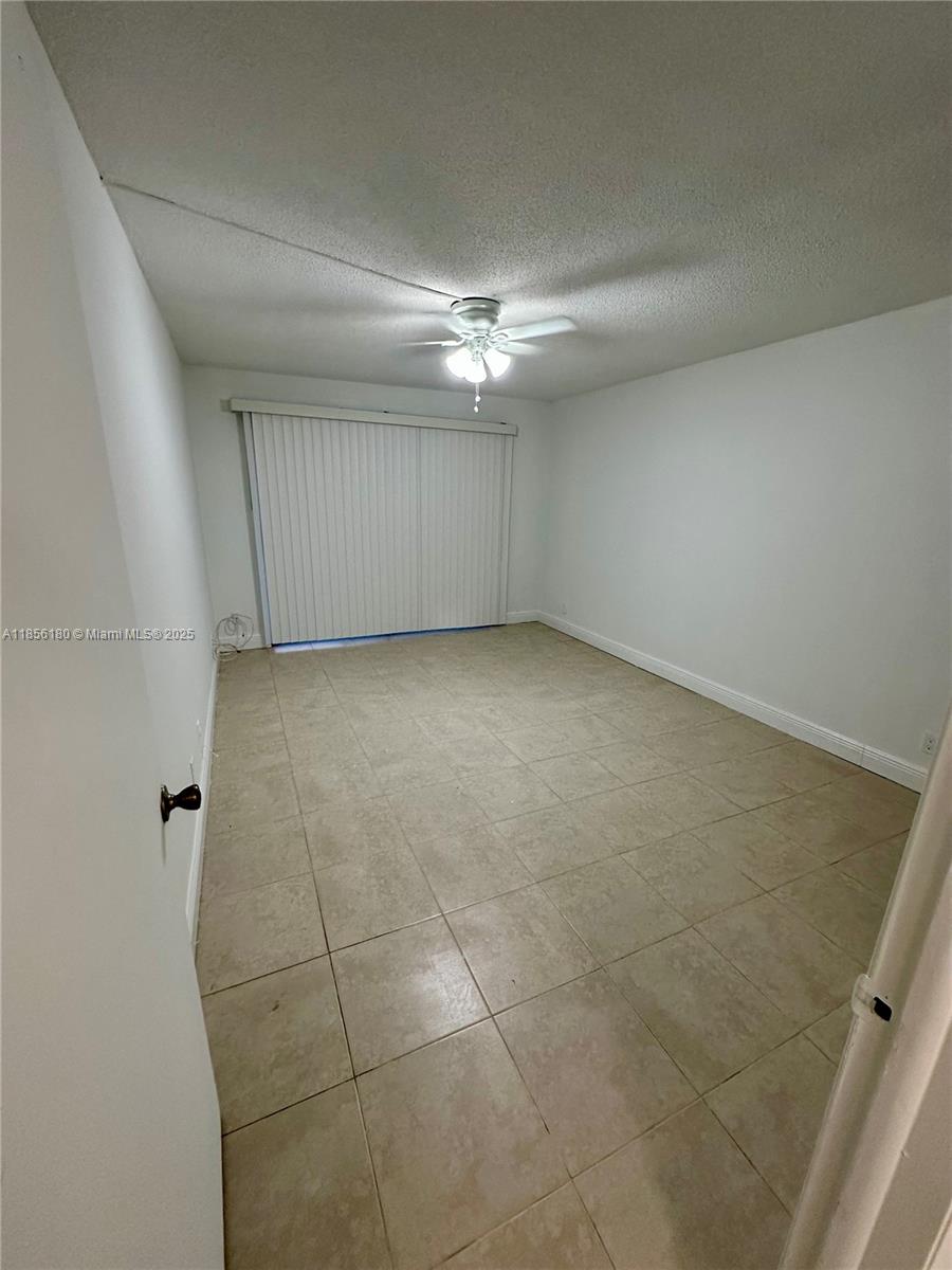603 South State Road 7, Unit 1E Margate, FL 33068 - Photo 4 of 8 an empty room with a ceiling fan and carpet