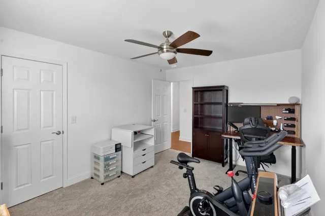 a view of a workspace with furniture and a ceiling fan