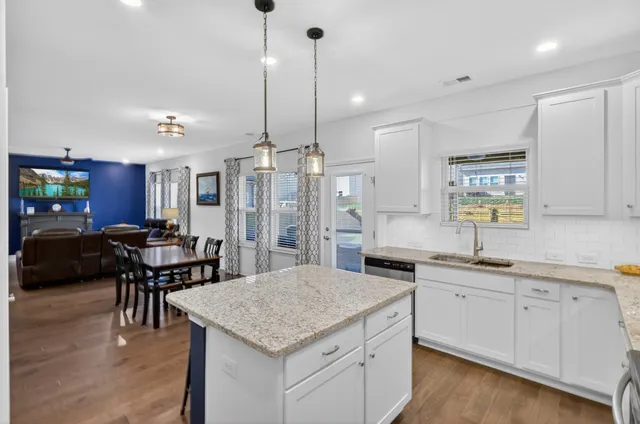 a kitchen with stainless steel appliances kitchen island granite countertop a sink a stove a dining table and chairs