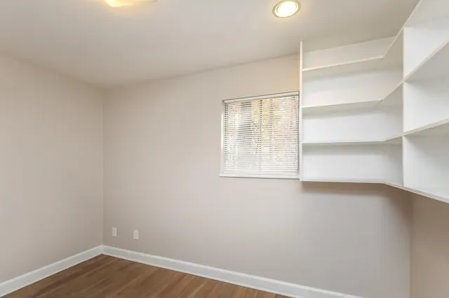 a view of an empty room with a window and wooden floor