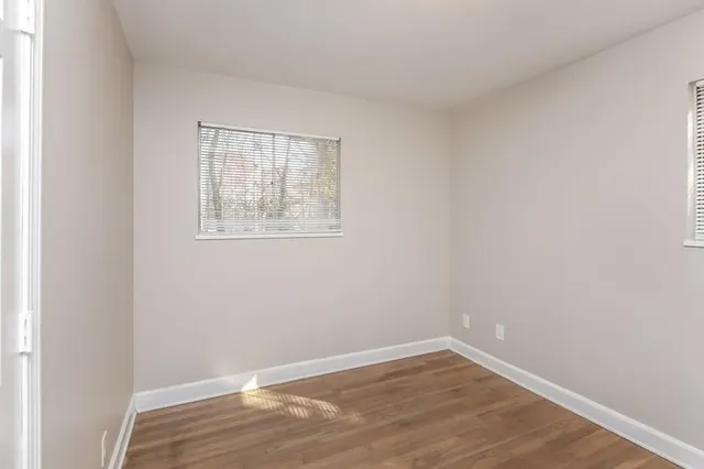 a view of an empty room with wooden floor and a window