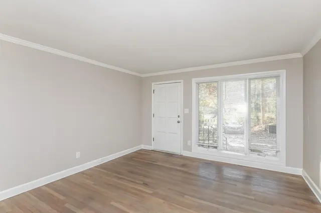 a view of an empty room with wooden floor and a window