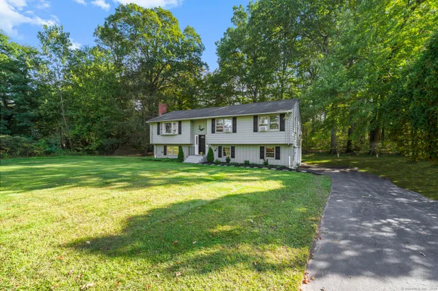 a view of a house with a big yard and large trees
