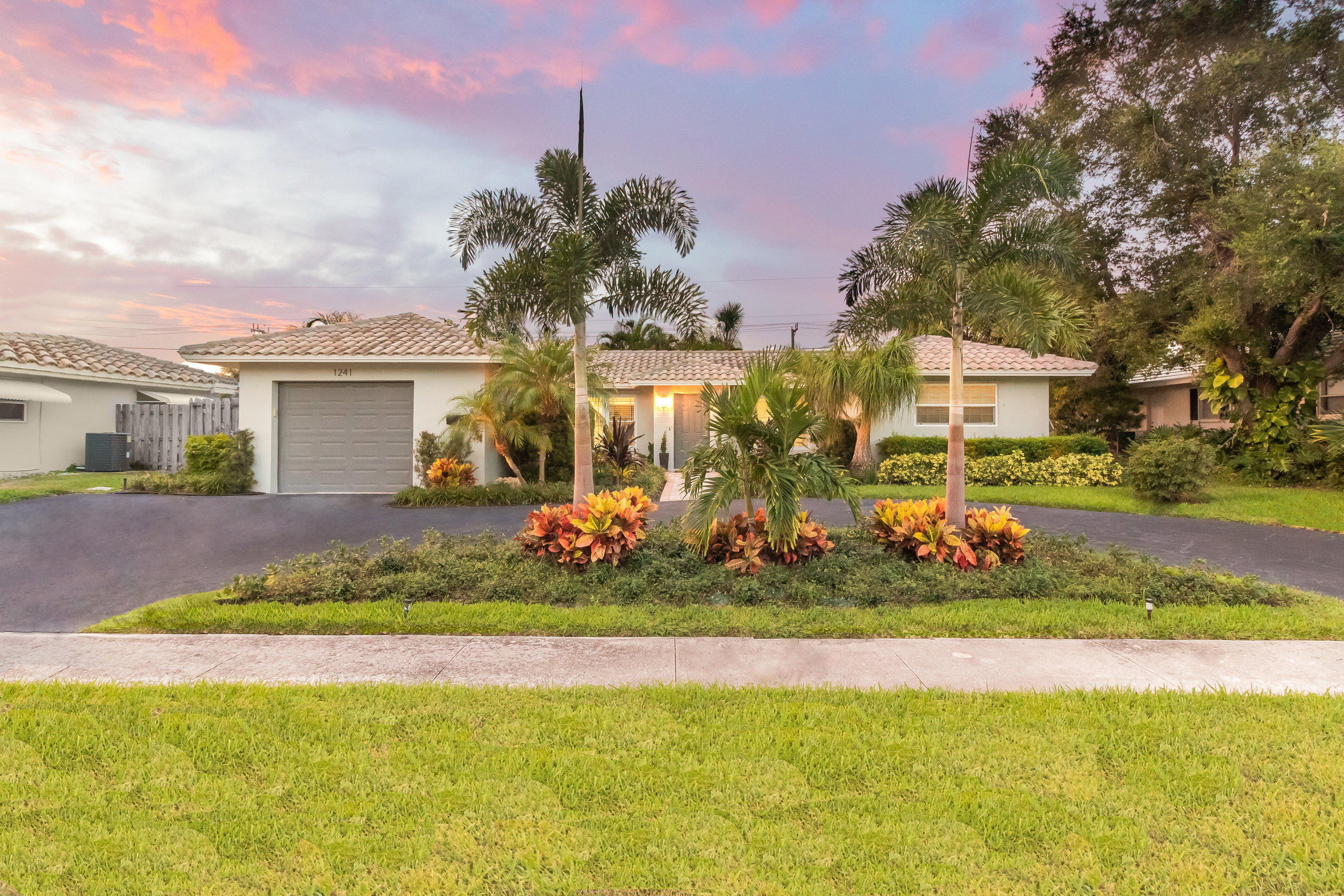 1241 Southwest 8th Street Boca Raton, FL 33486 - Photo 20 of 22 a front view of a house with a yard and fountain in middle of the road