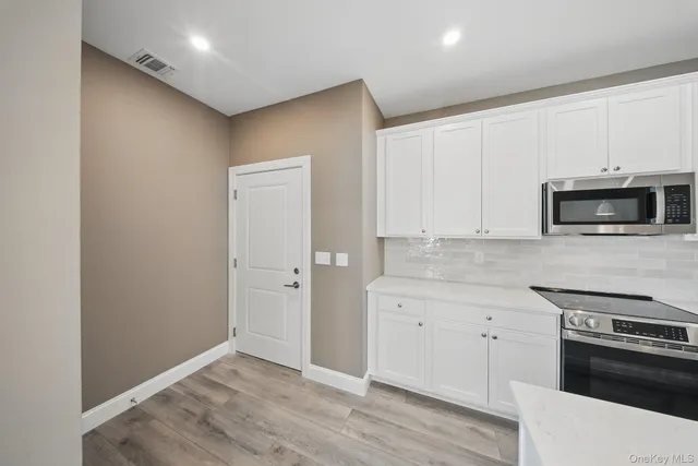 a kitchen with granite countertop white cabinets and stainless steel appliances