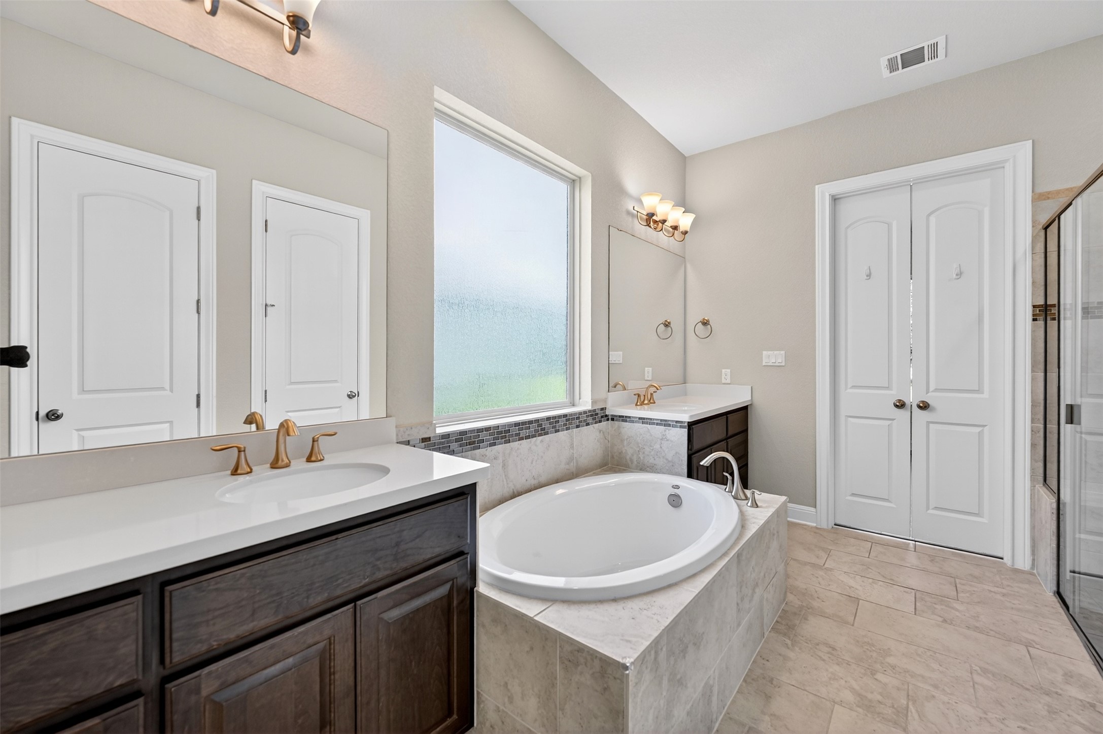 1201 Positano Pass Leander, TX 78641 - Photo 26 of 40 Bathroom featuring dual vanities with white countertops, dark wood cabinetry, and gold-toned fixtures